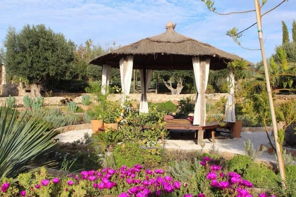 Cenador y cama balinesa con flores en los jardines del cortijo